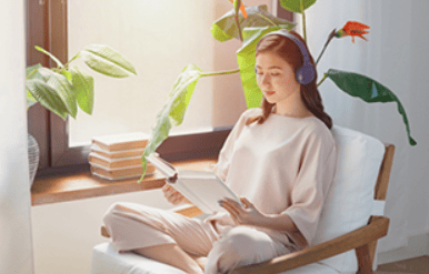 女性がヘッドホンで音楽を聴きながら読書をしてる写真